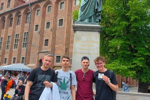 Czterech młodych chłopaków z pomnikiem Mikołaja Kopernika